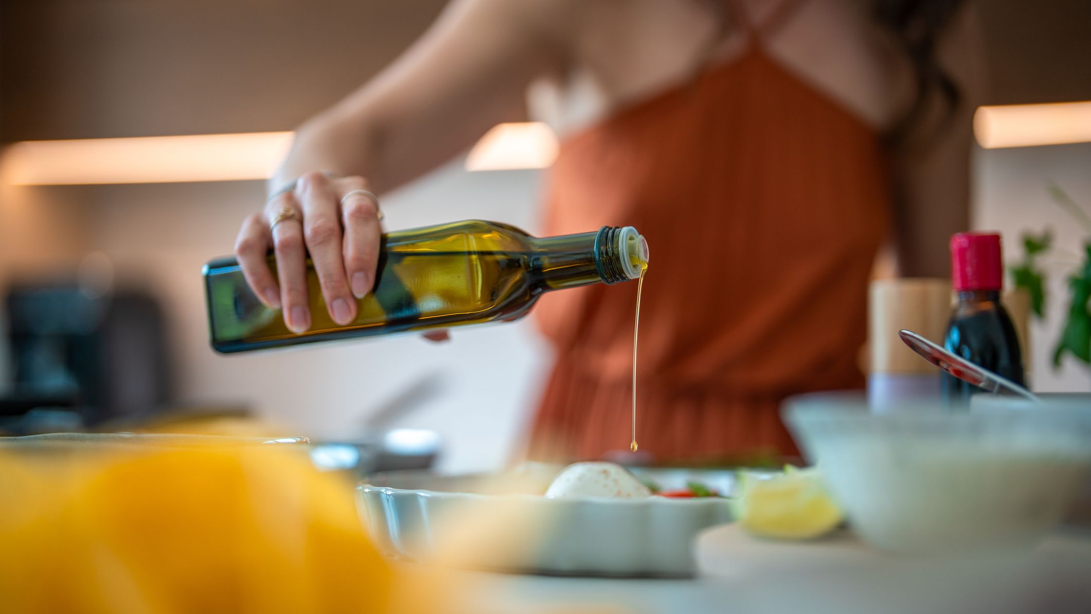 Woman pours olive oil into dish on a kitchen counter