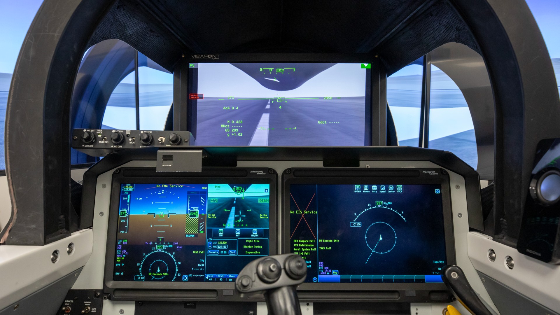 three rectangular display screens inside a cramped aircraft cockpit