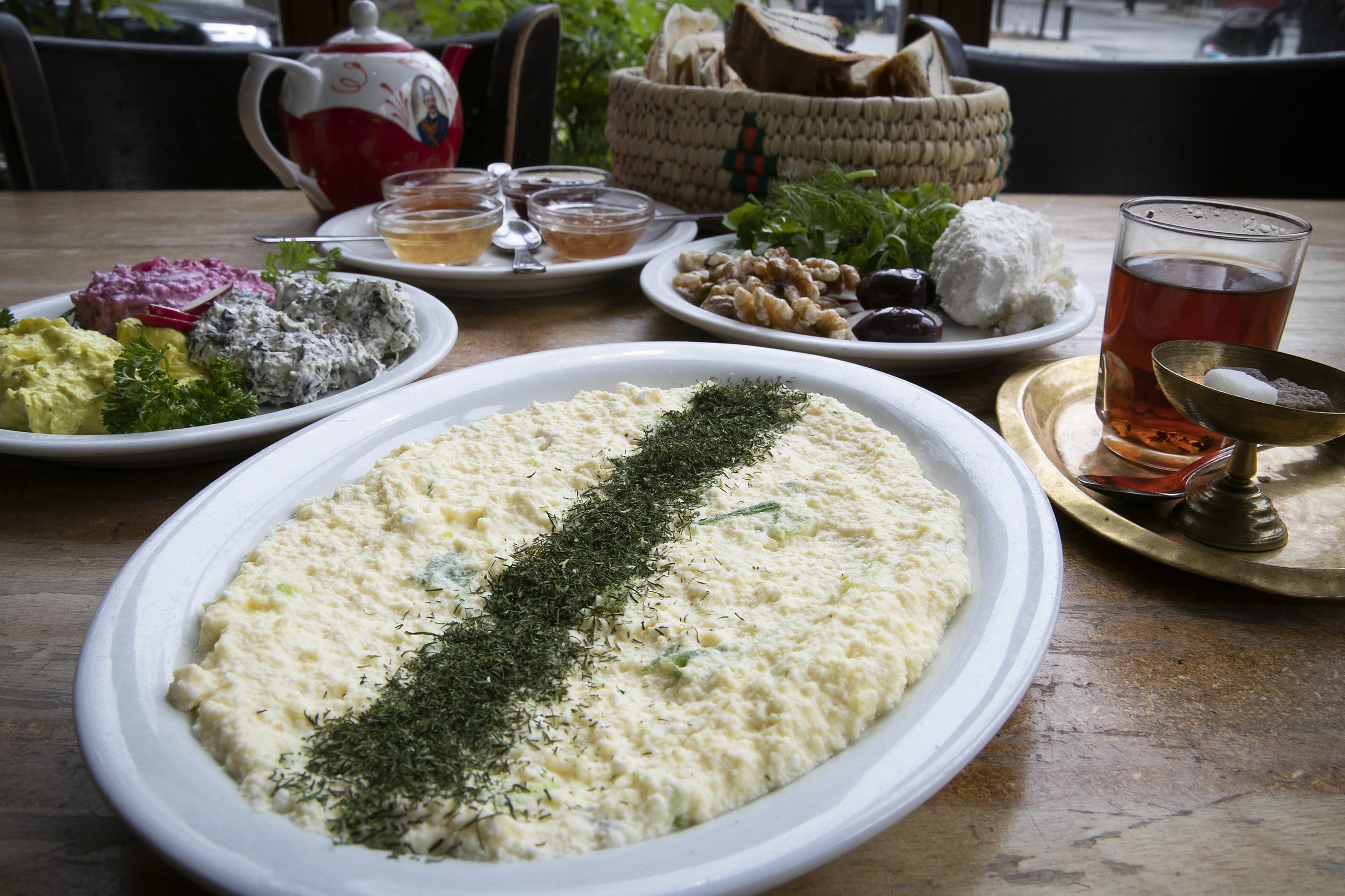 An omelette on a table with tea, bread and vegetables
