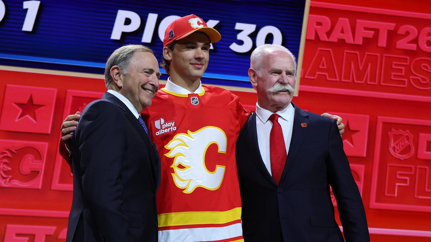 Jun 26, 2026; Buffalo, New York, USA; Jack Hextall reacts beside NHL commissioner Gary Bettman and former NHL player Lanny McDonald after being selected with the thirtieth pick in the first round of the 2026 NHL Draft by the Calgary Flames at KeyBank Center. Mandatory Credit: Timothy T. Ludwig-Imagn Images
