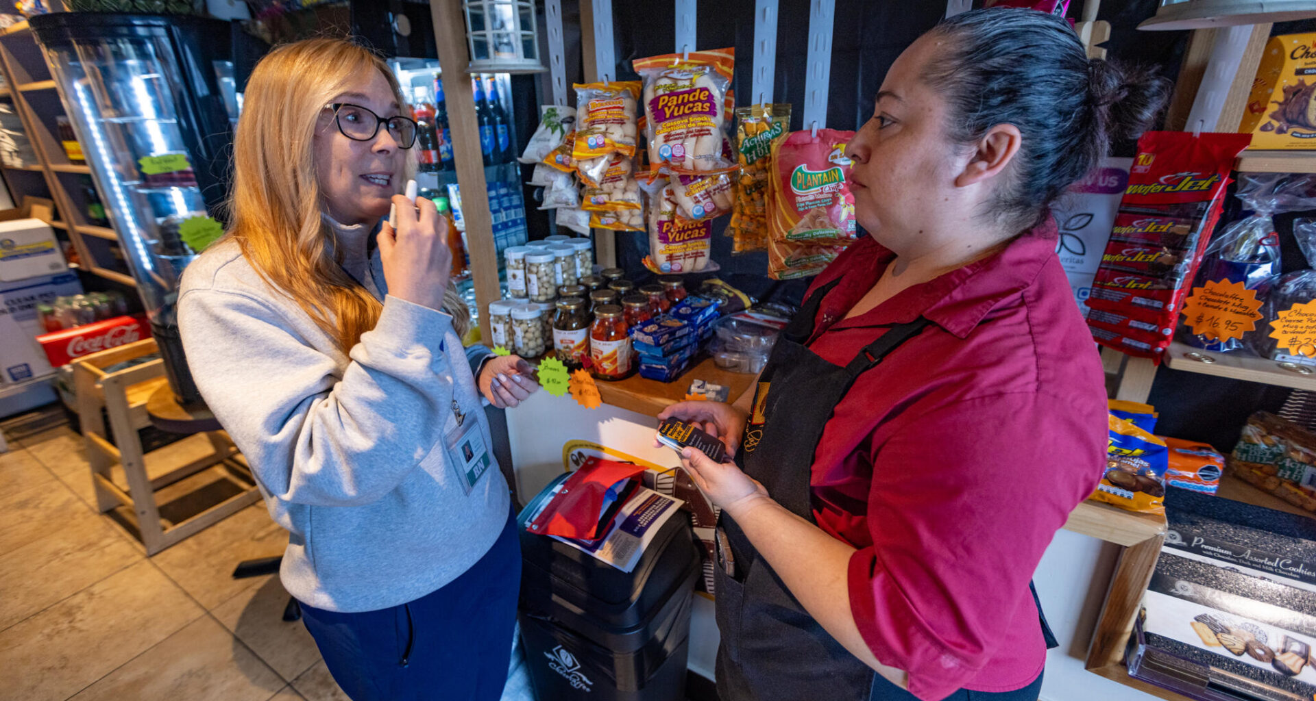 Registered nurse Denise Hartley, co-founder of Atlantic Hill Nursing and Wellness, demonstrates to cafe owner Diana Cardona how to administer naloxone. (Jesse Costa/WBUR)