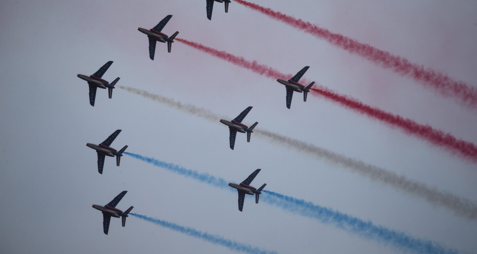 French jets conduct a flyby trailing coloured smoke.