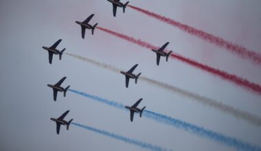 French jets conduct a flyby trailing coloured smoke.