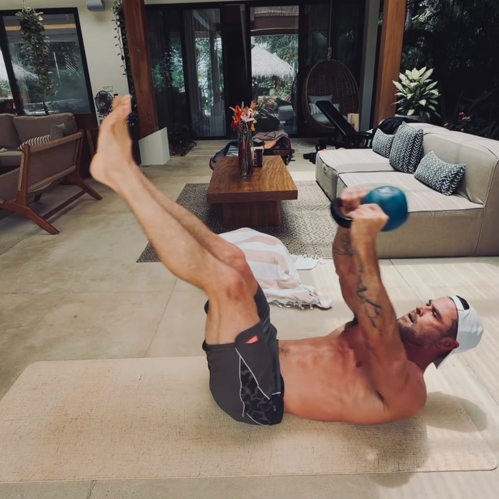 man exercising with a kettlebell in a living room. man exercising with a kettlebell in a living room.