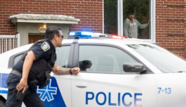 A resident watches from a window as Montreal police officer deploys at a shooting in Côte-des-Neiges.