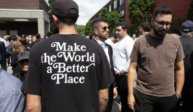 "Make the World a Better Place" is inscribed on the back of a T-shirt worn by a mourner outside the Paperman funeral home where family and friends gathered for the funeral of Michel Mizrahi