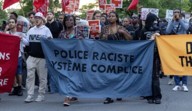 Anti-police racism marchers hold banners in Montreal North