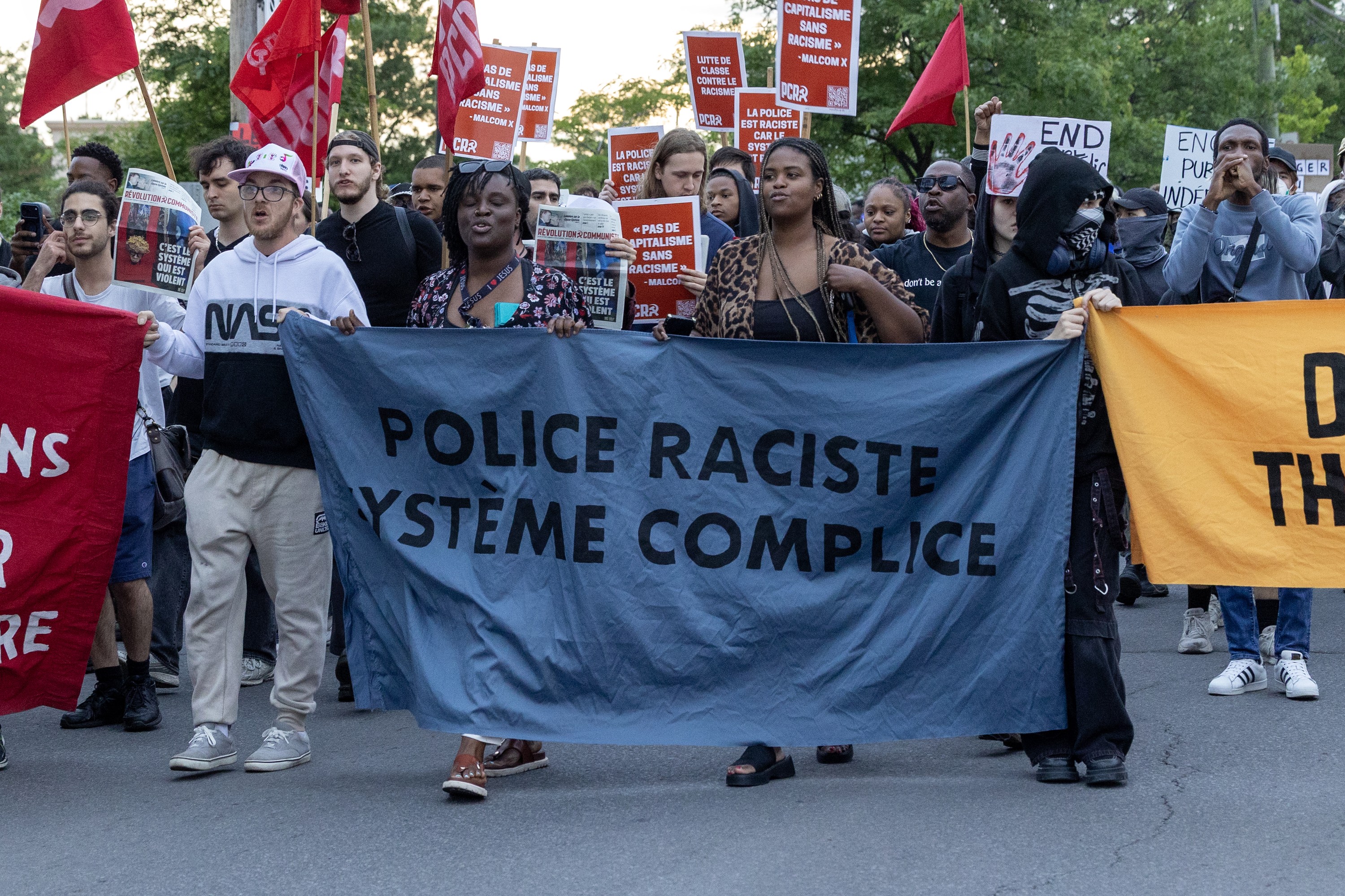 Anti-police racism marchers hold banners in Montreal North