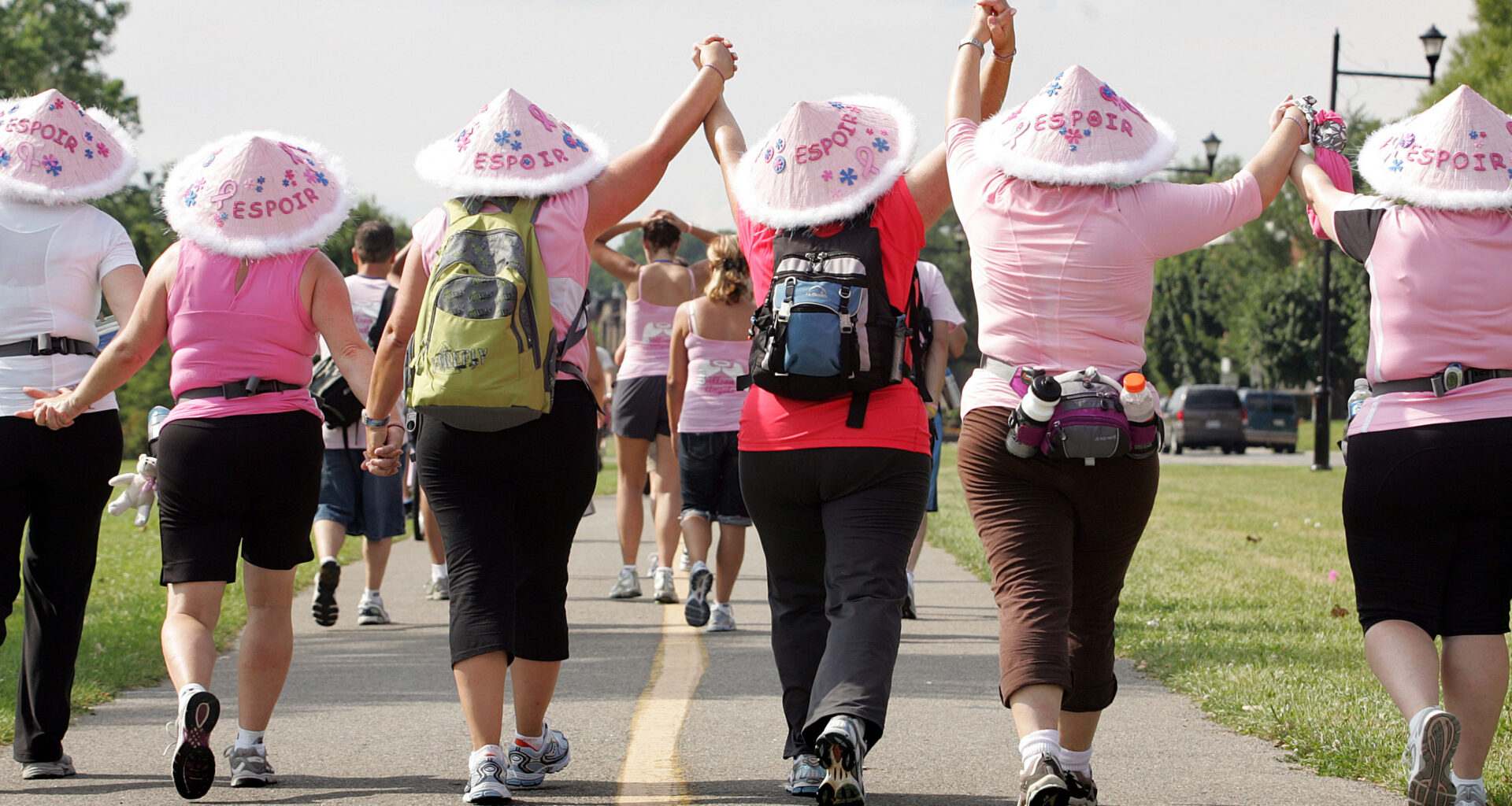 Women holding hands and wearing pink hats participate in the Weekend to End Breast Cancer in 2009.