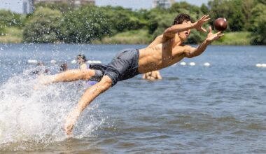A man jumps nearly horizontally out of the water to catch a football