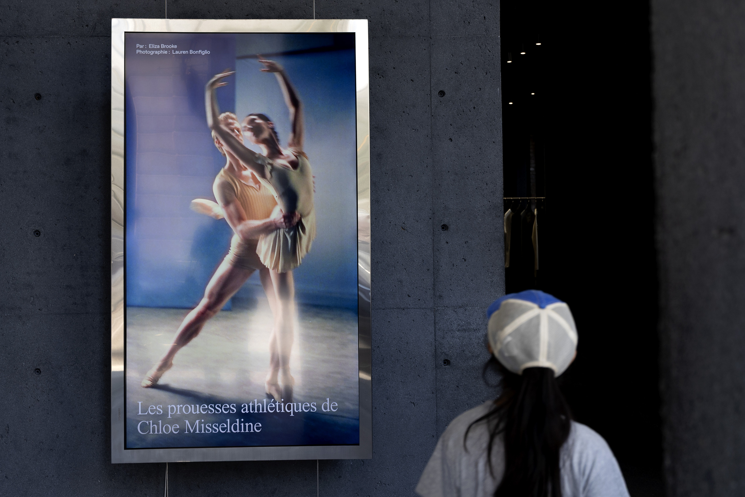 A person looks at a digital display screen showing two ballet dancers.