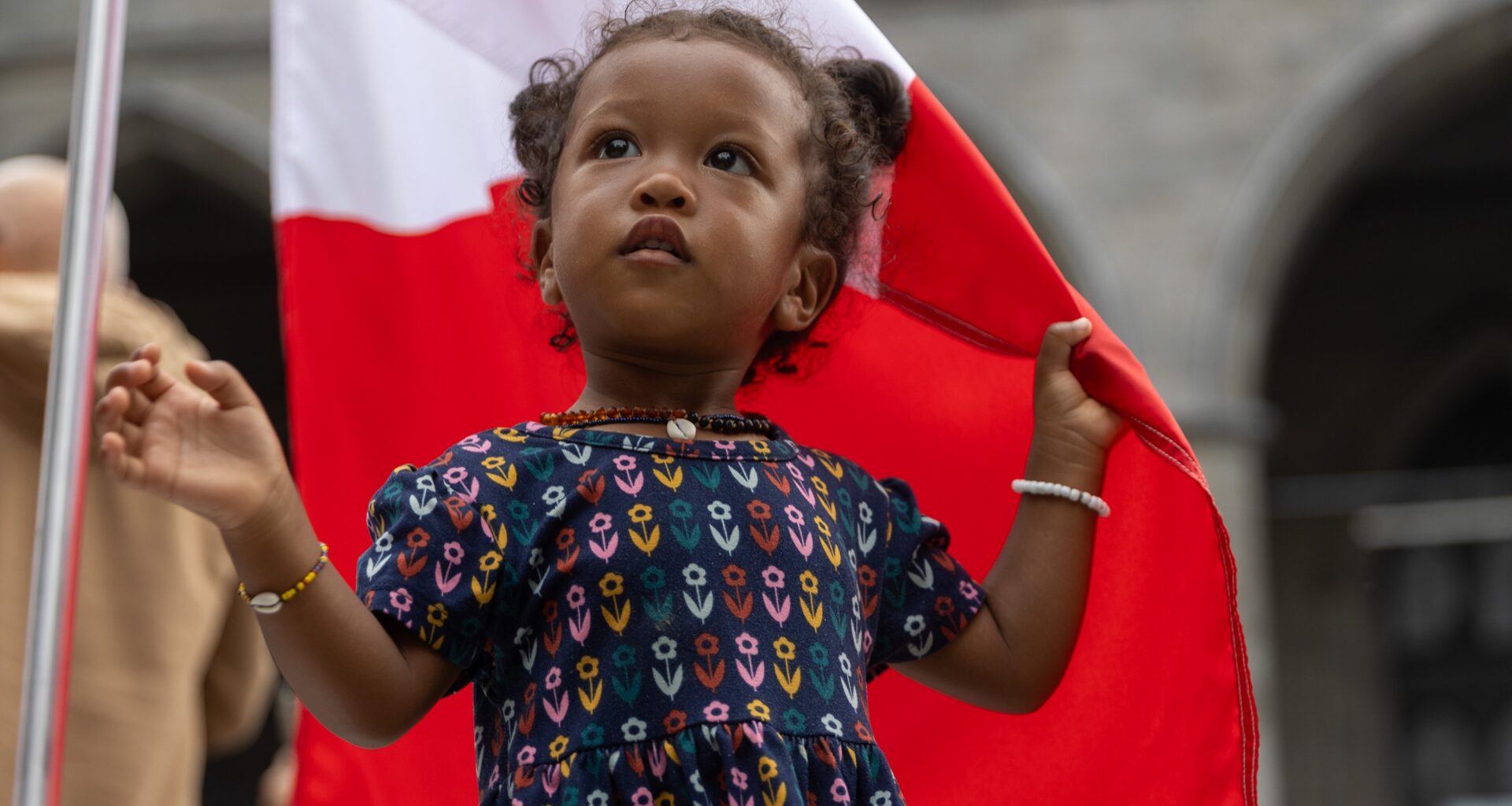 Young girl clutches a large Canadian flag at Canada Day parade in Montreal