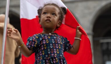Young girl clutches a large Canadian flag at Canada Day parade in Montreal