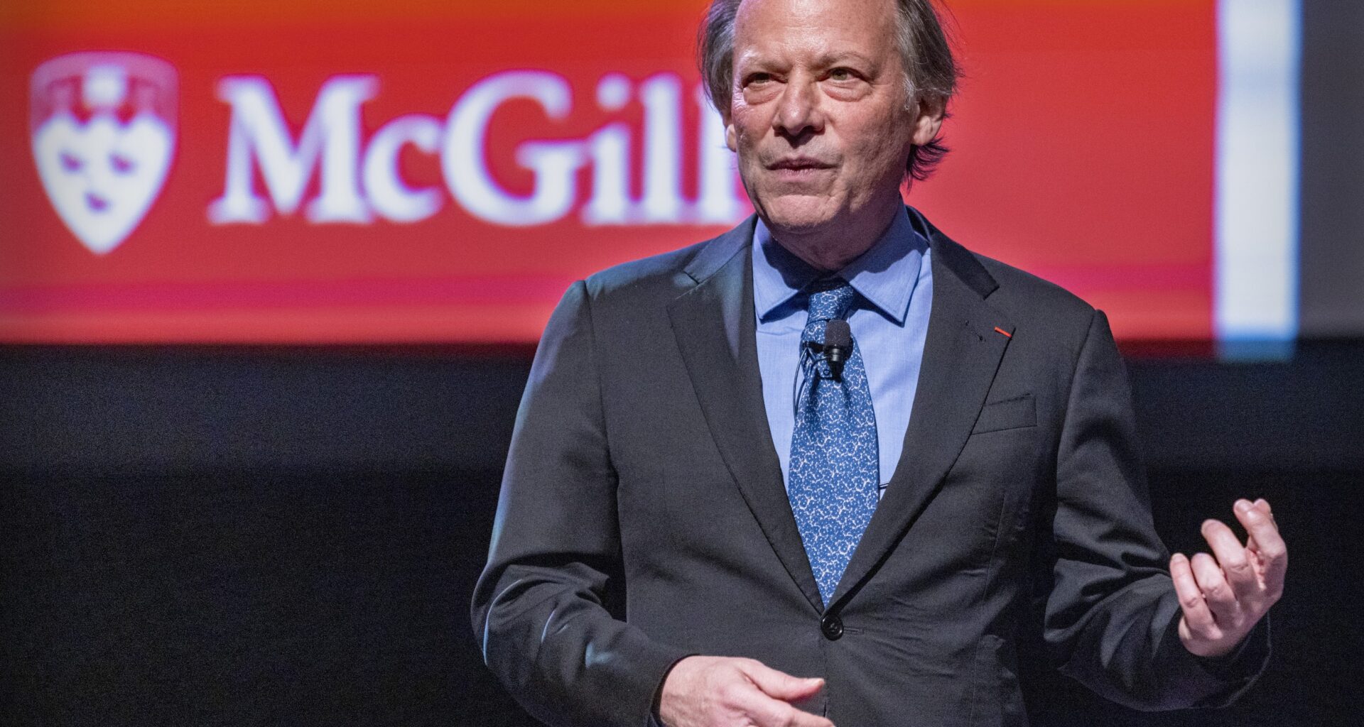 Man stands on McGill stage delivering a lecture.