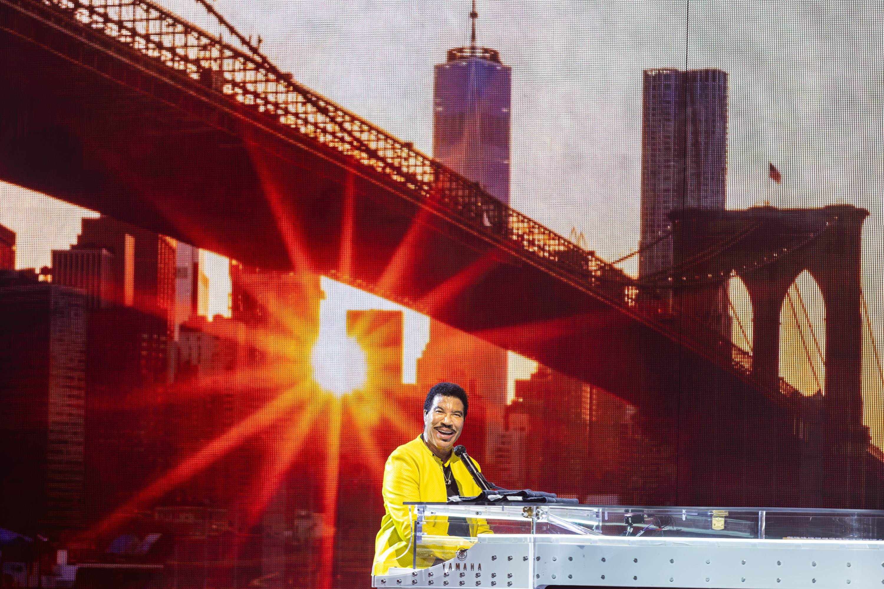 Lionel Richie at the piano in front of a projection of the New York syline