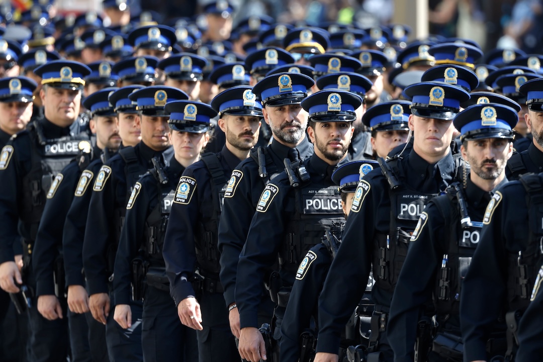 Dozens of police officers walk in a procession.