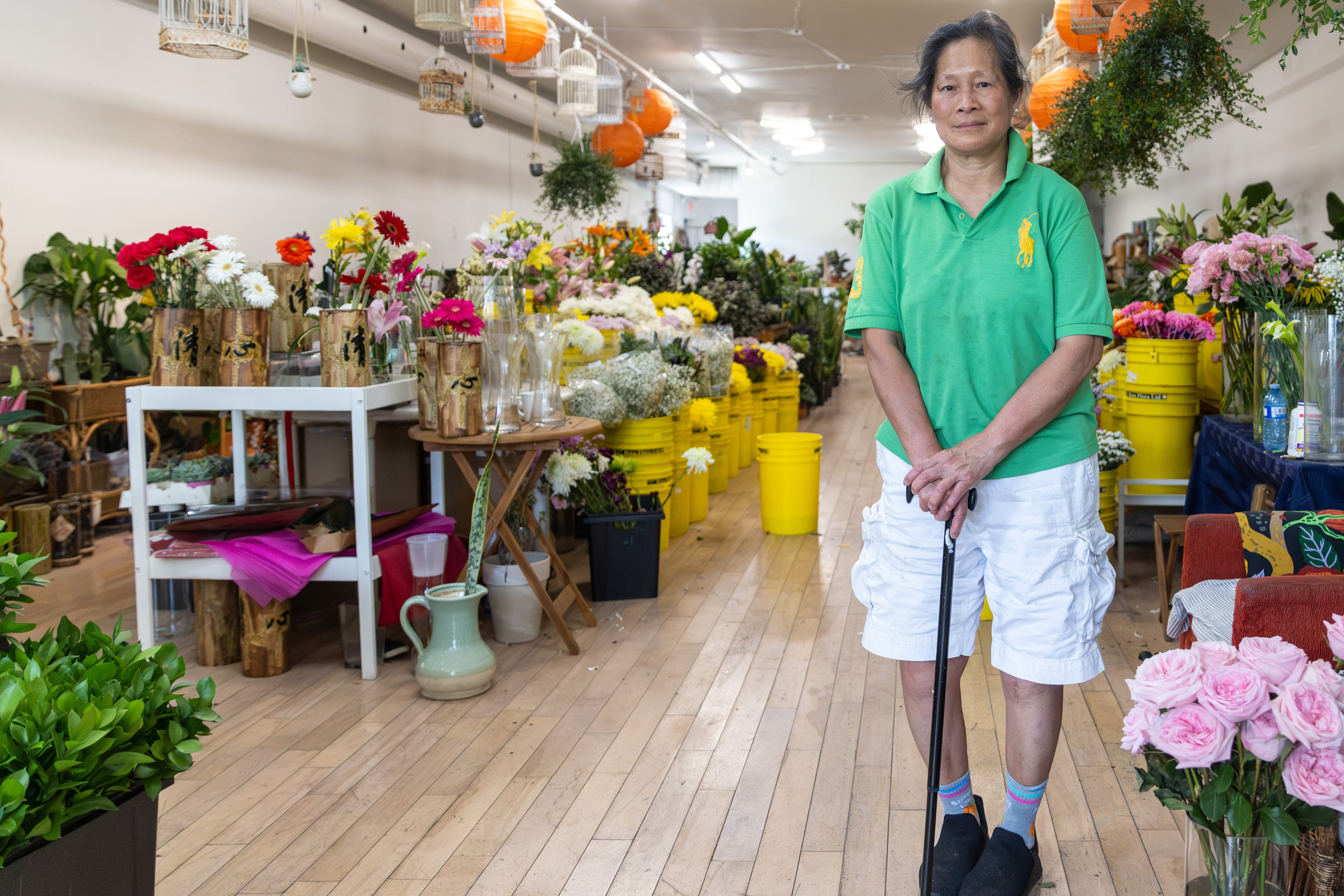 A woman with a cane stands in a flower shop.