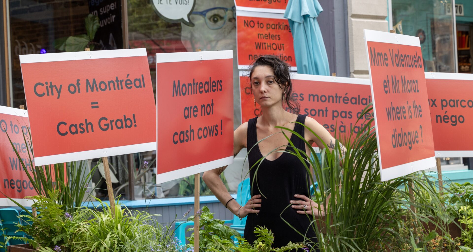 Young woman stands amid bright red protest signs.