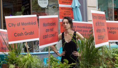 Young woman stands amid bright red protest signs.