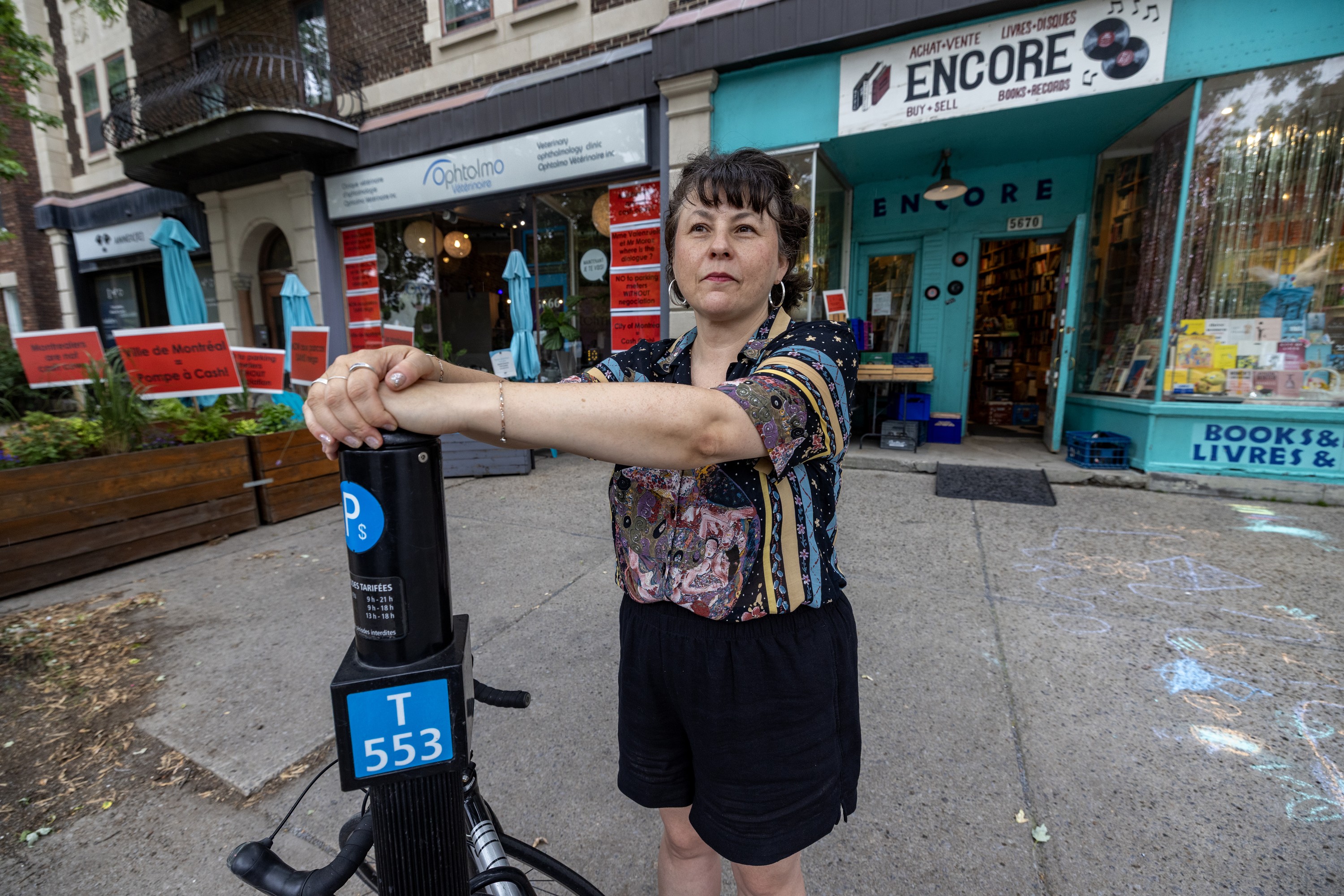 Woman leans against parking meter post on street