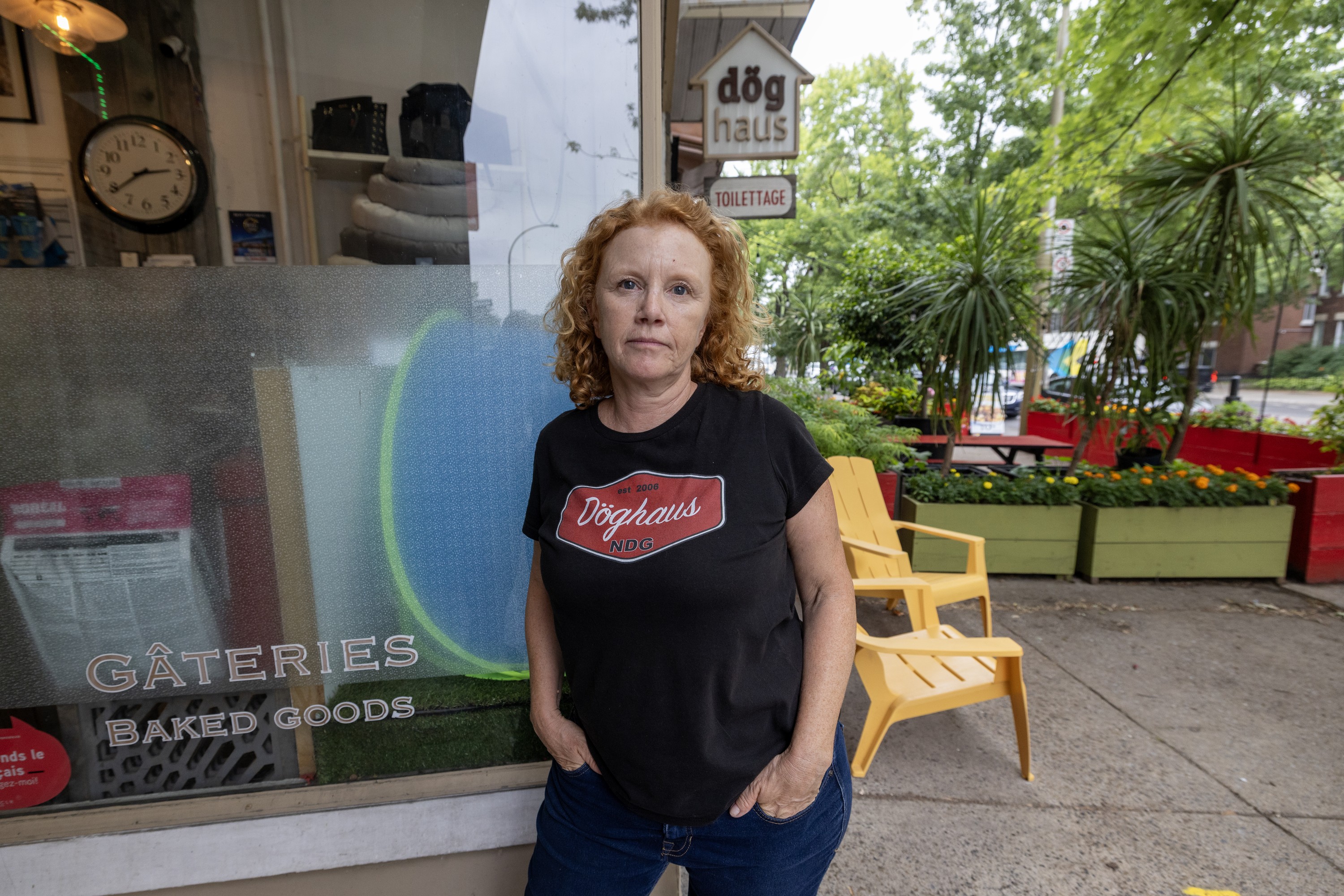 Woman stands outside shop, hands in jeans pockets