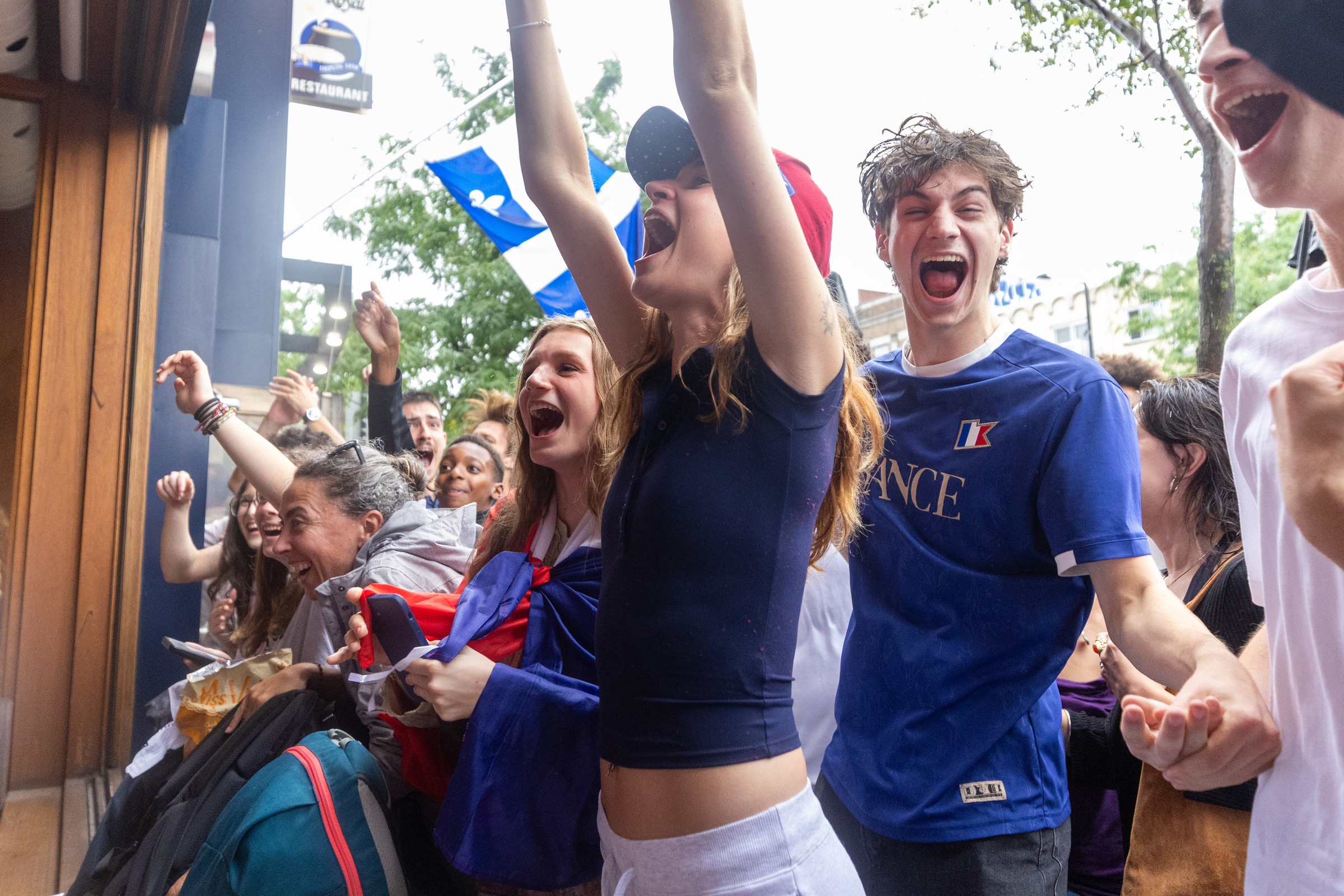 People dressed in blue cheer while watching outside a bar.