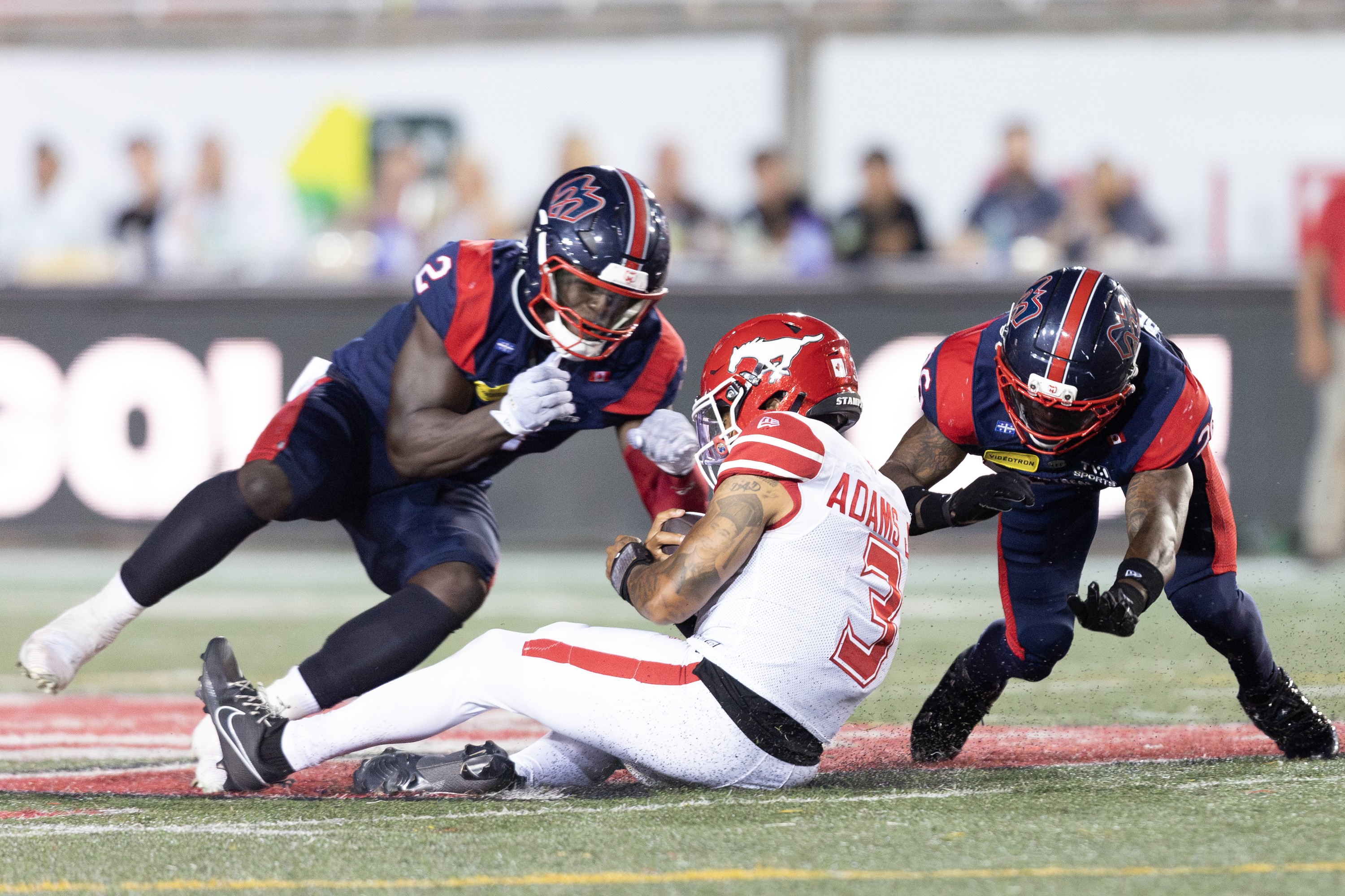 Stampeders quarterback Vernon Adams Jr. slides to avoid a hit from Alouettes linebacker Micah Awe, left, and defensive-back Lorenzo Burns.