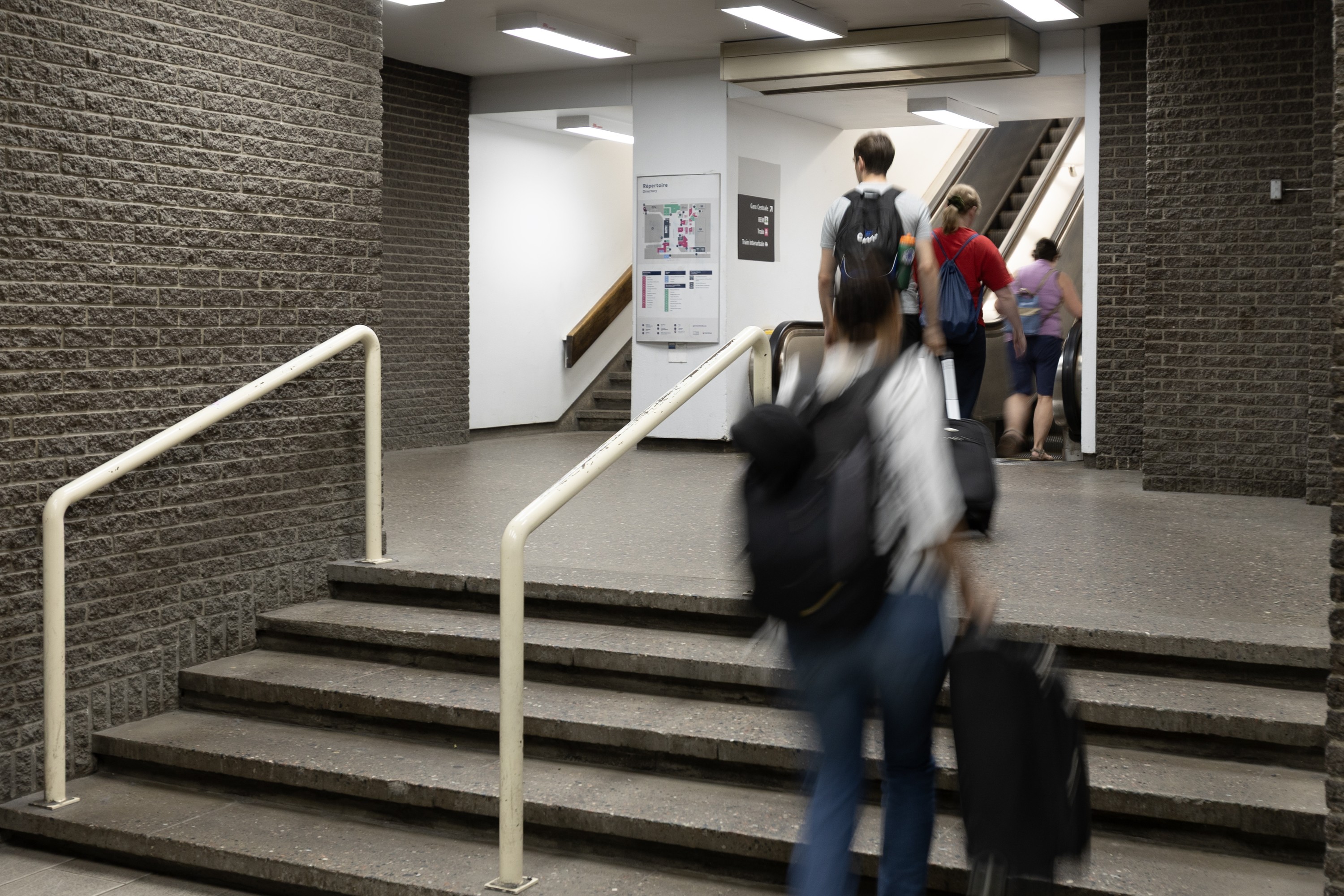 Underground corridor shows steps leading to an escalator.