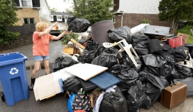 Risa Weigersberg throws a bag of garbage onto the growing pile of flood-damaged items outside her Dauphin St. home in Dollard-des-Ormeaux on June 21, 2026.