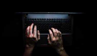 Hands on a laptop keyboard in the dark.
