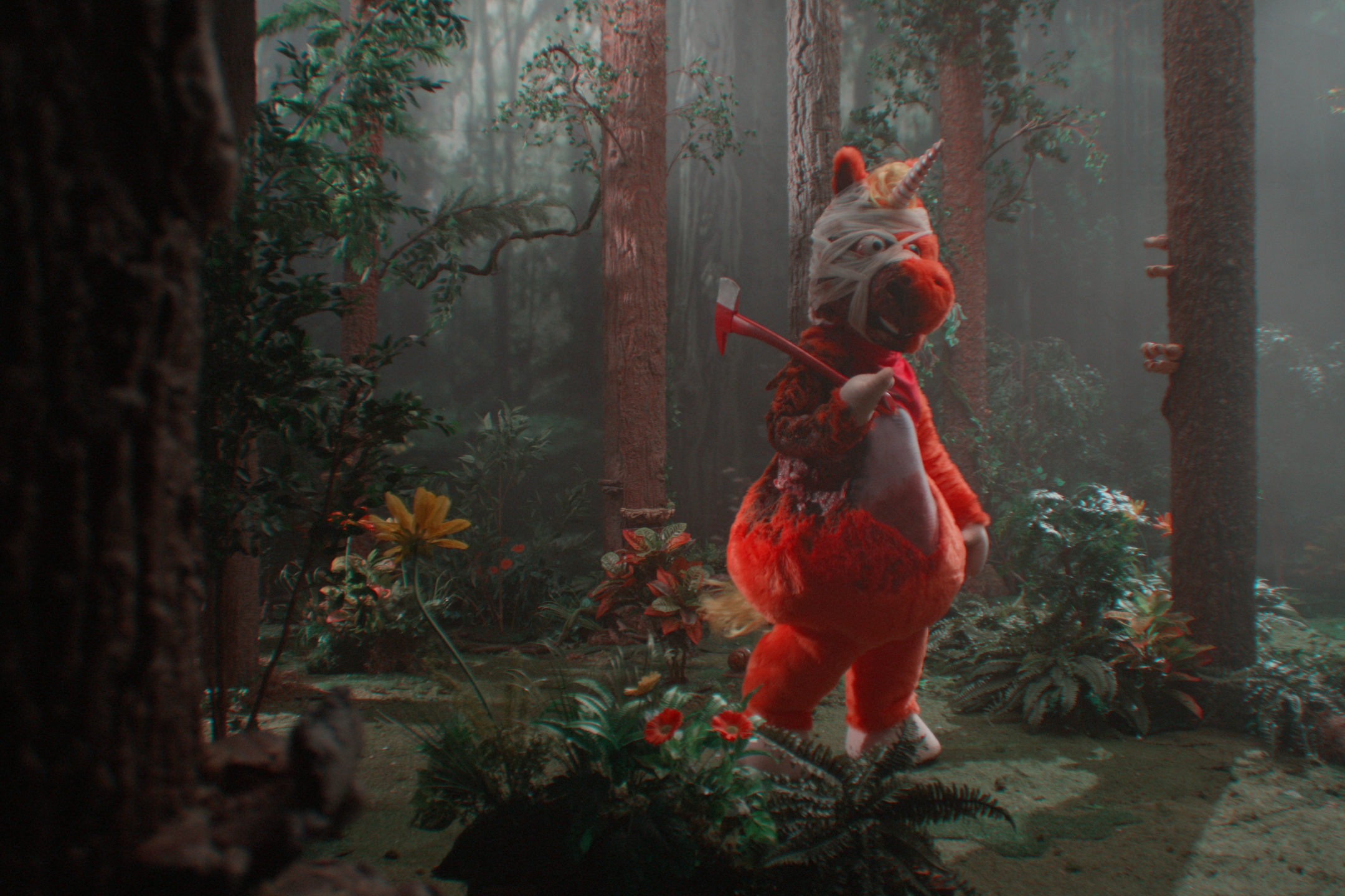 A red, unicorn-like character with a bandage on their head carries an axe as they walk in a forest, in a scene from the film Buddy