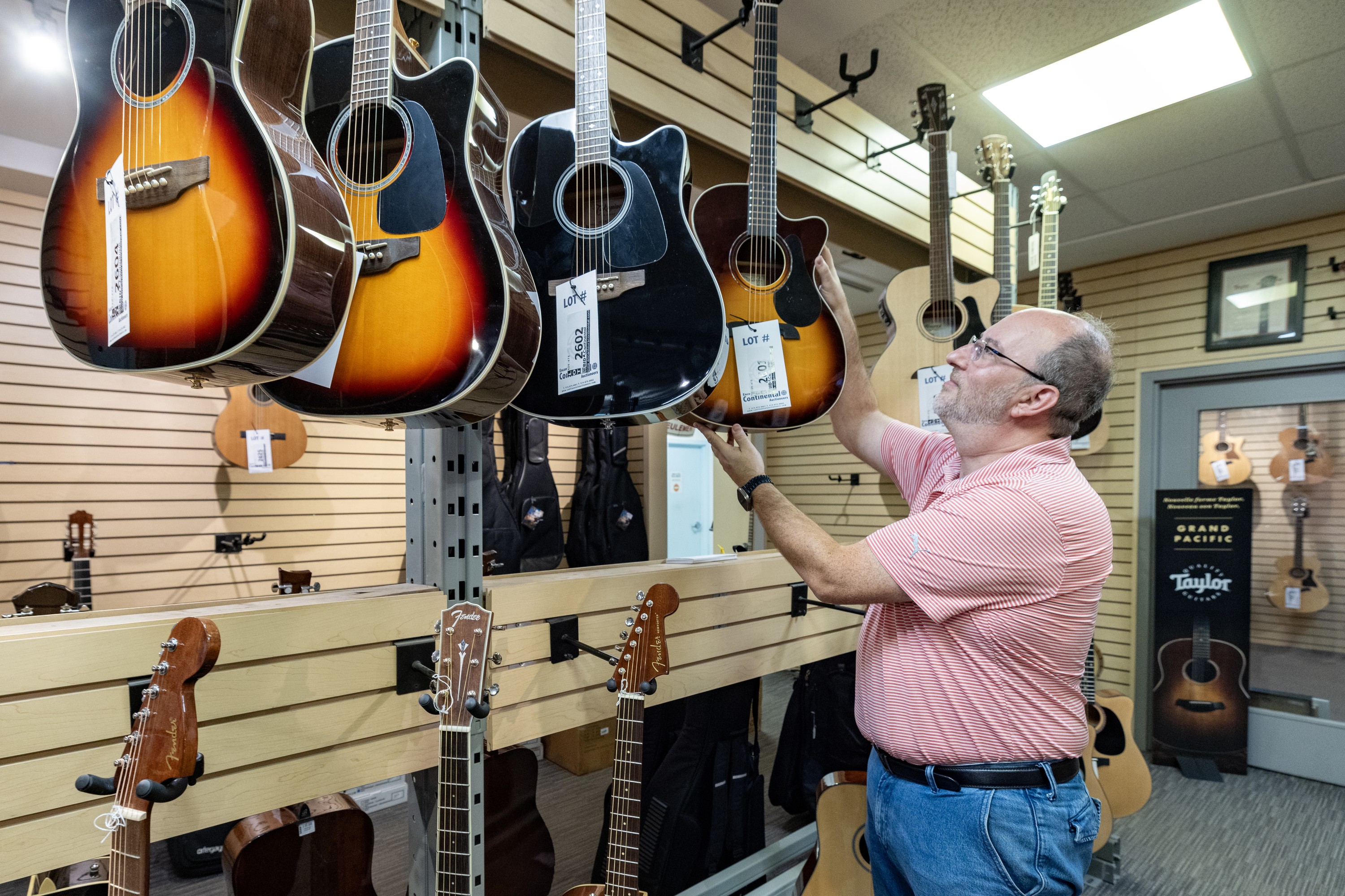 A man hangs an acoustic guitar on a rack at a music store