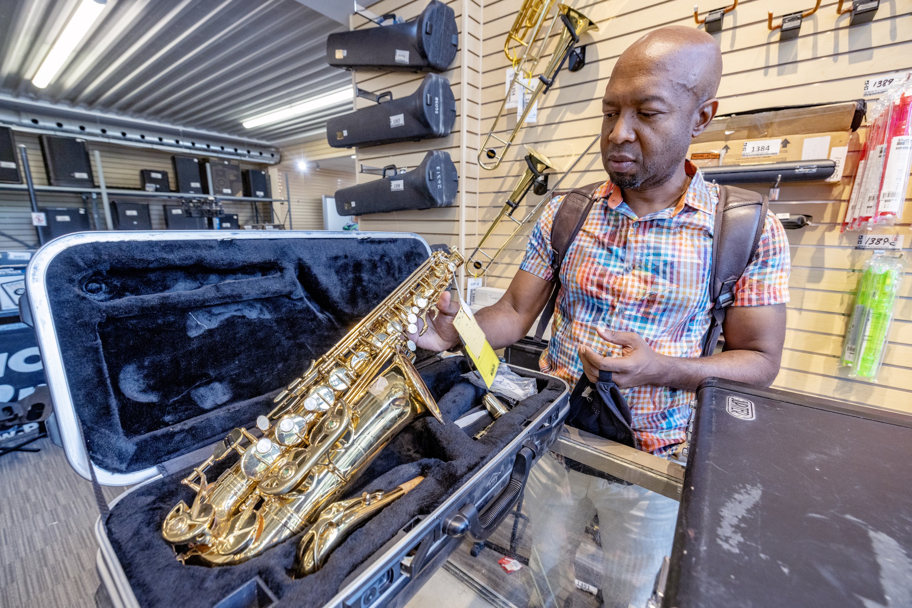 A man inspects a saxophone at a music store