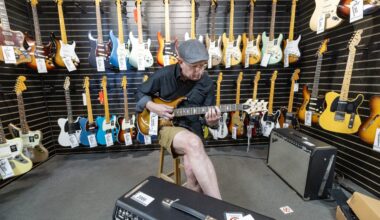 A man tries an electric guitar as he sits in a music store in front of racks of other guitars