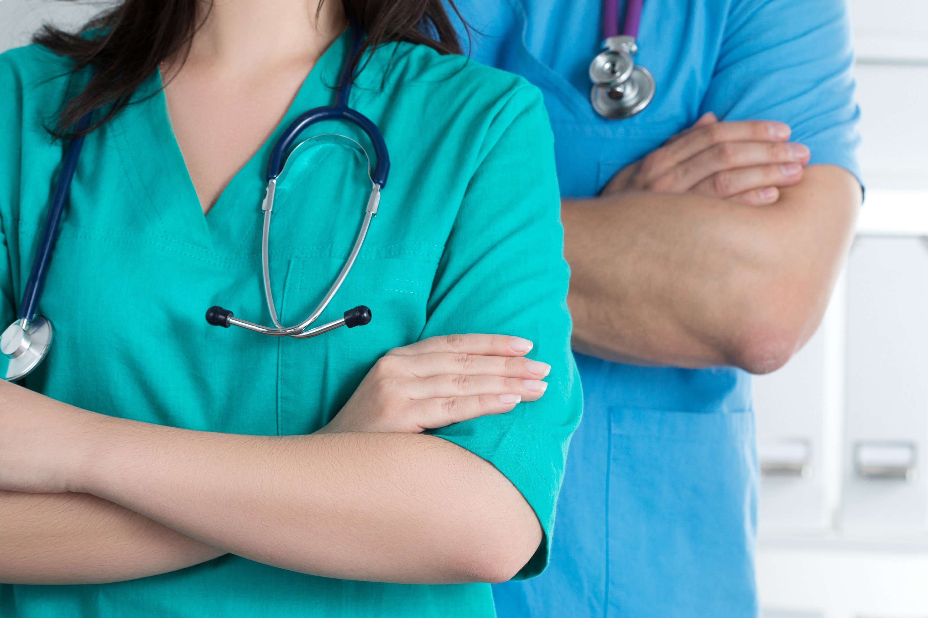 stock photo shows two physicians, one female and one male, with arms crossed and stethoscopes