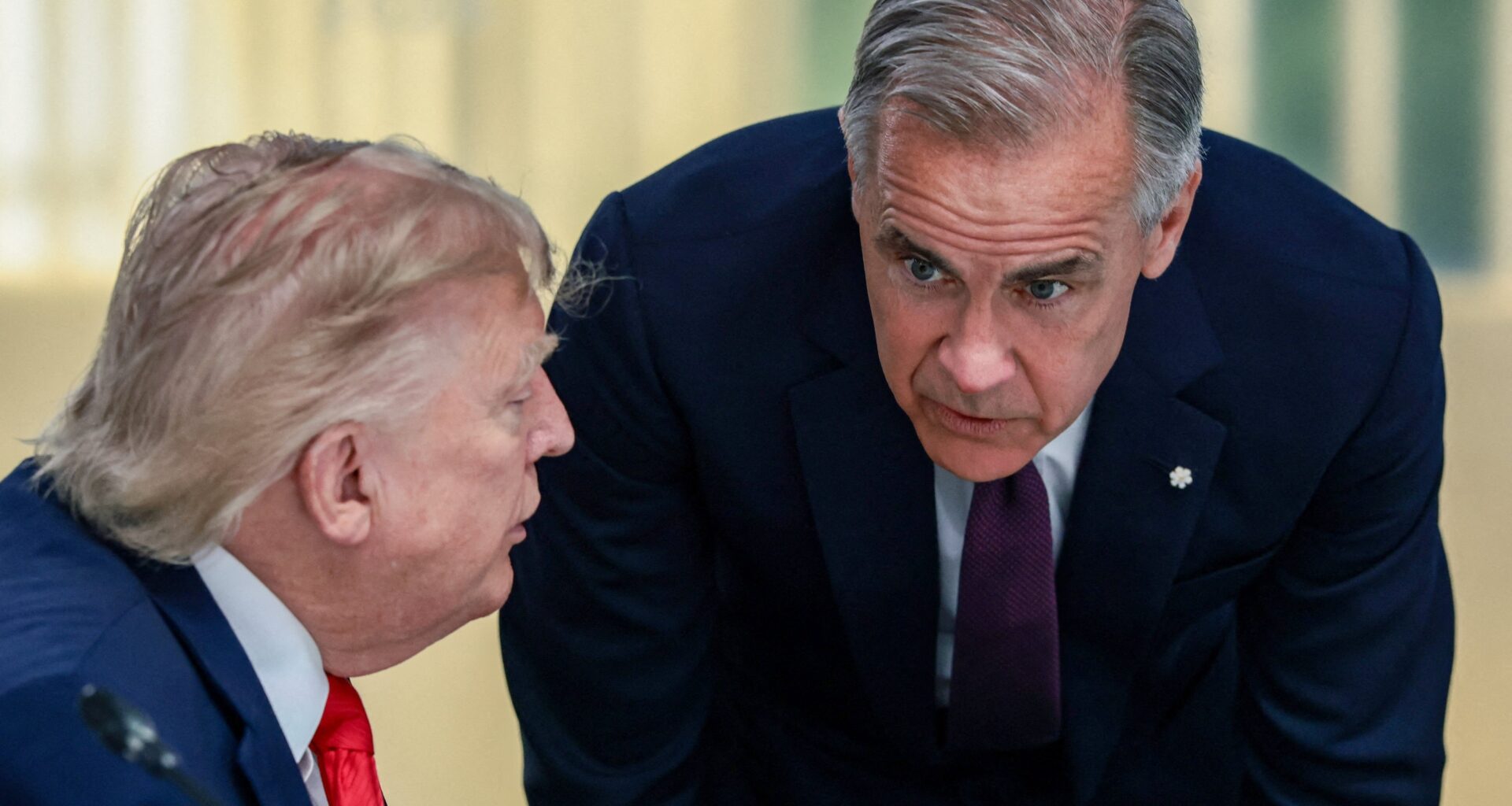 Prime Minister Mark Carney bends to listen to a sitting Donald Trump during a work lunch at the G7 summit in France
