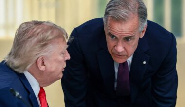 Prime Minister Mark Carney bends to listen to a sitting Donald Trump during a work lunch at the G7 summit in France
