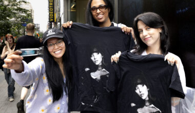 Two young women hold up black T-shirts with Ariana Grande