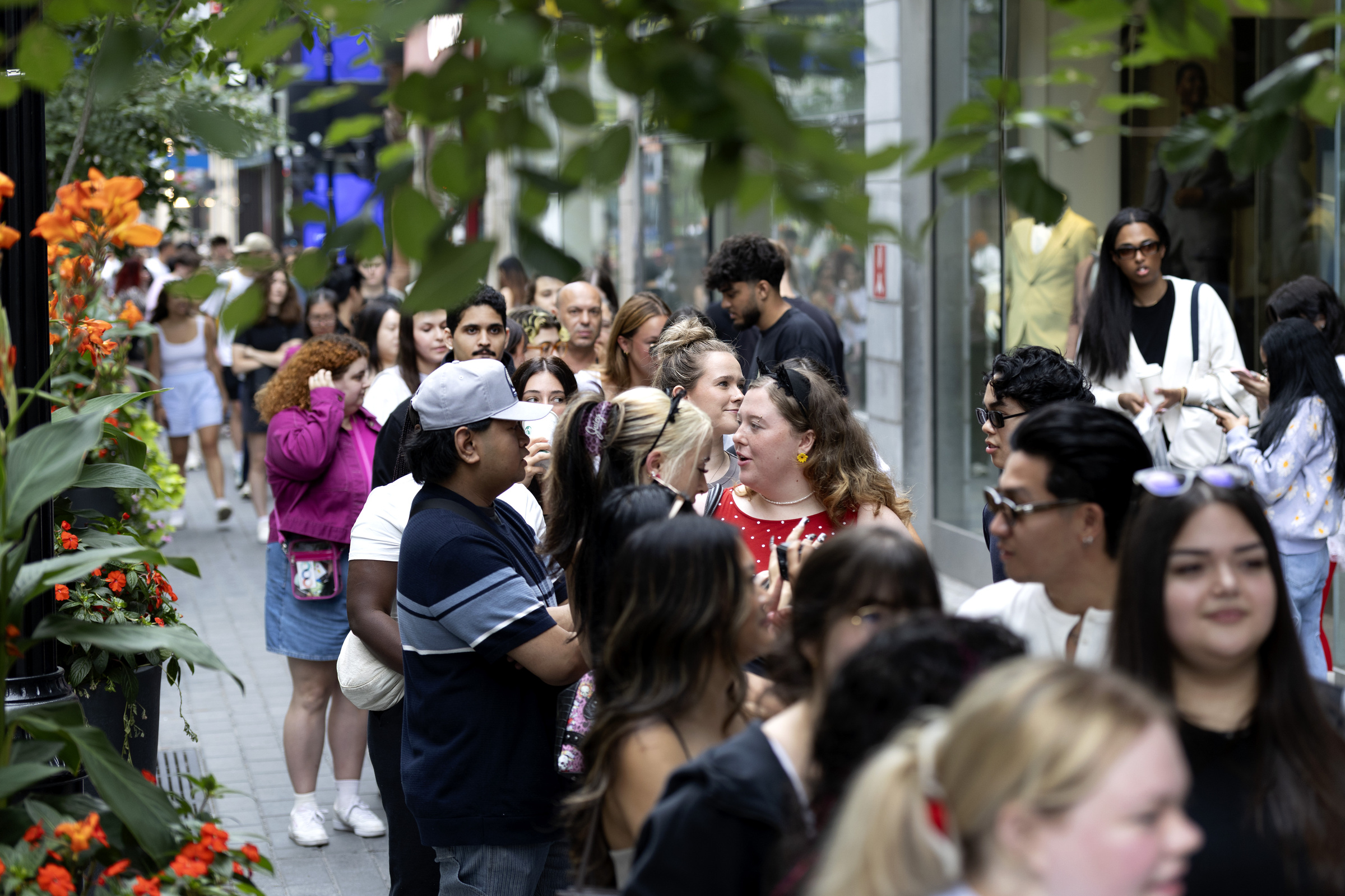A lineup of people on a downtown sidewalk.