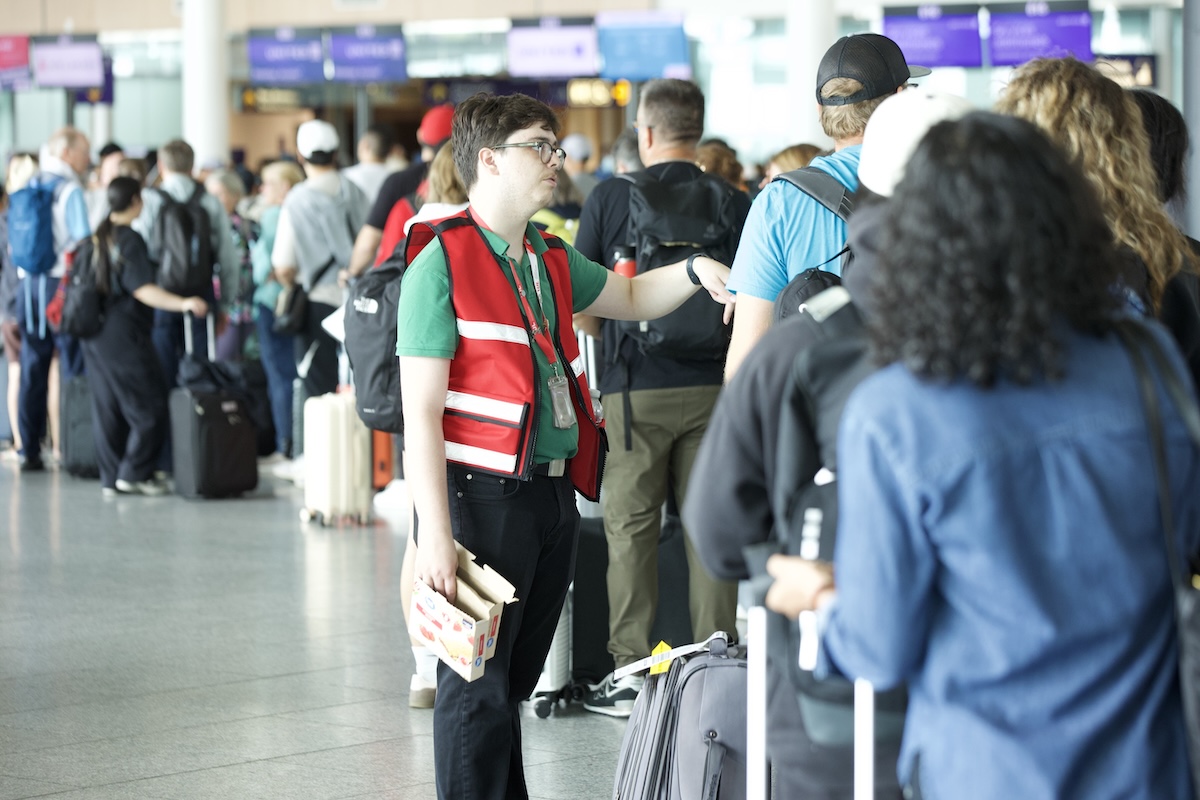 An airport worker speaks to people lined up at customs.
