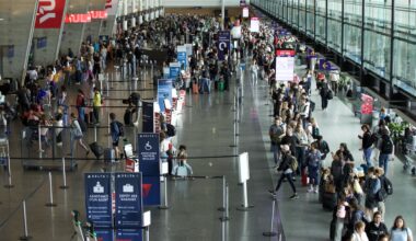 From above, hundreds of people are seen packed into lineups at an airport.