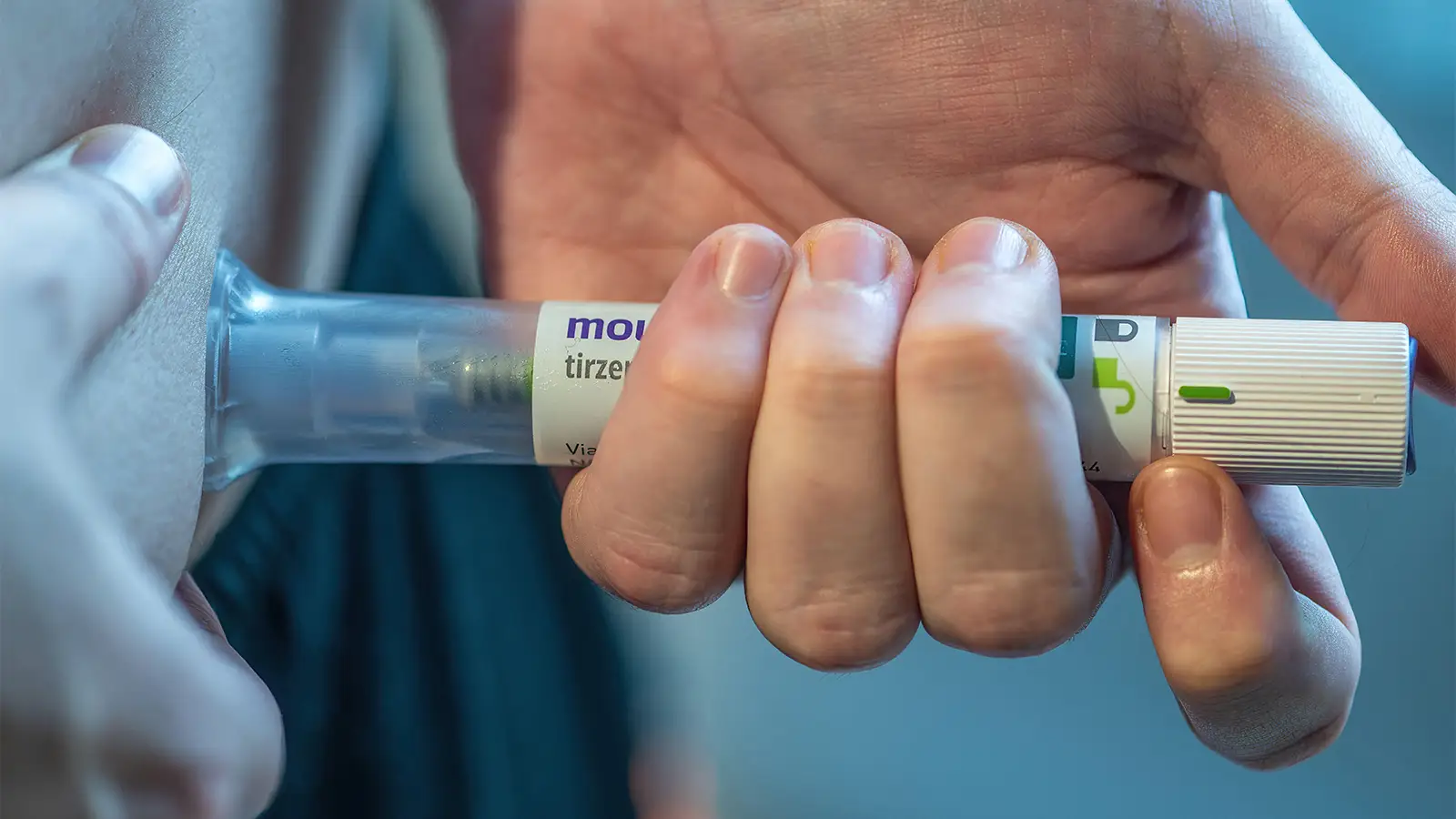 A photo of a man self-injecting his abdomen with a tirzepatide injection pen.