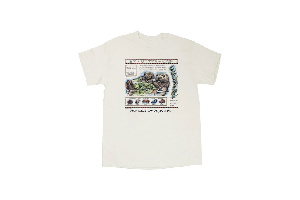 White t-shirt with an illustration of sea otters and information about them from the Monterey Bay Aquarium.