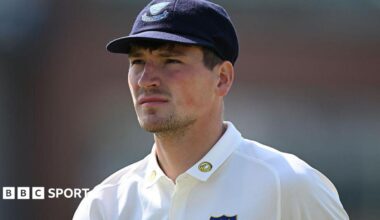 Henry Crocombe looks on in white Sussex shirt and dark blue Sussex cap