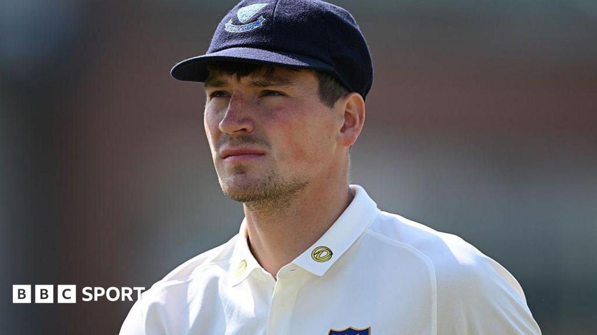 Henry Crocombe looks on in white Sussex shirt and dark blue Sussex cap