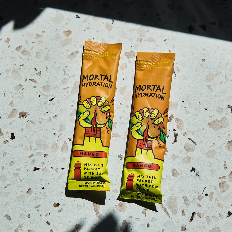Two packets of Mortal Hydration mango-flavored drink mix on a speckled surface.