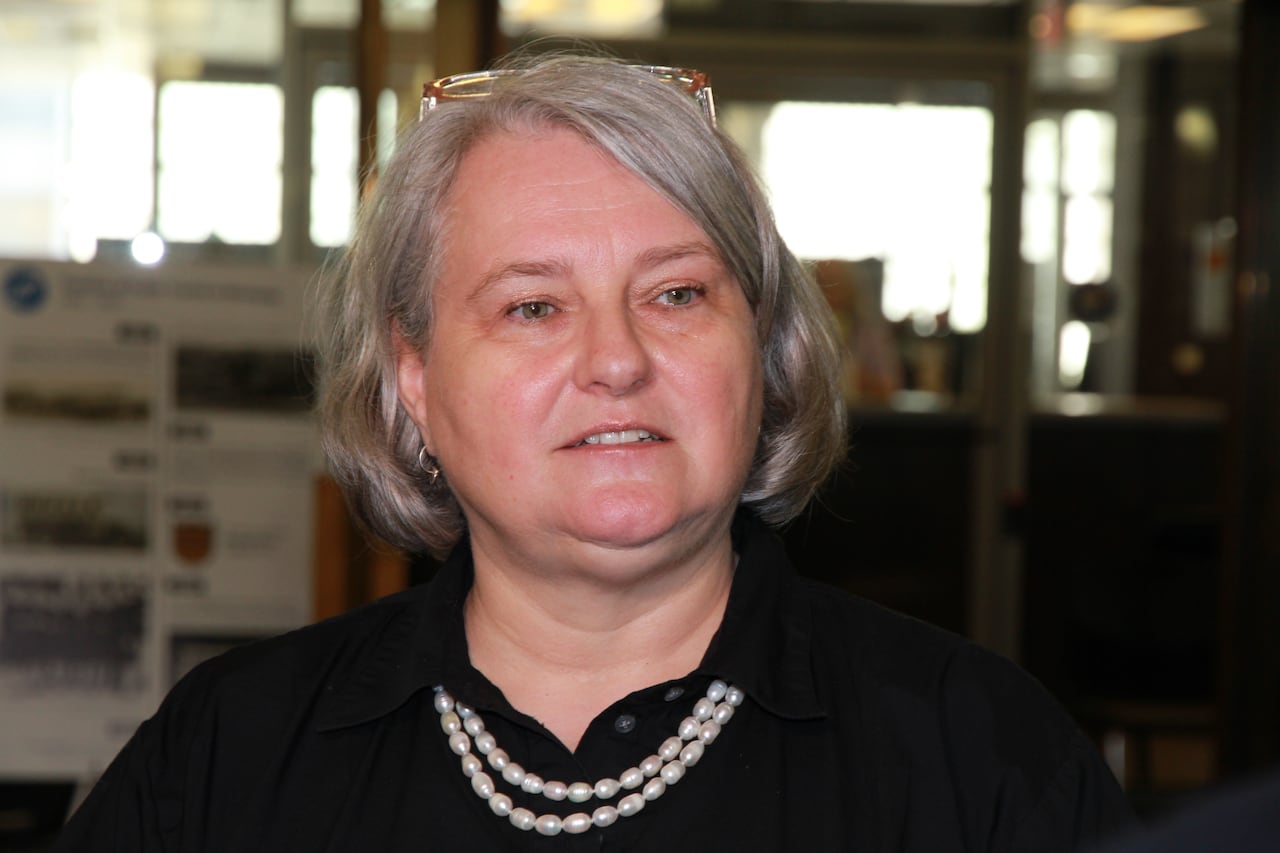 A woman with grey hair is speaking.