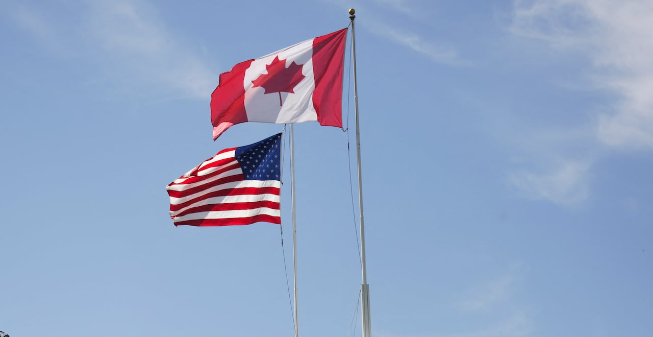 Canadian and U.S. flags fly atop a building.
