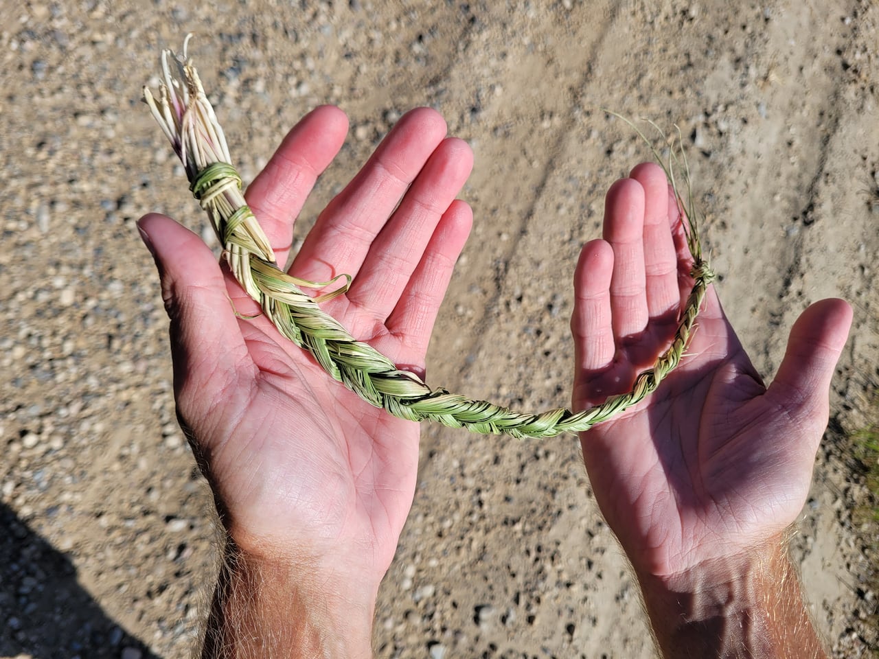 A pair of hands holding a braid of grass.