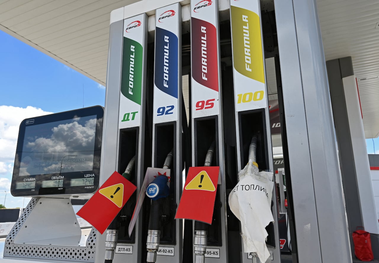 Four pumps at a gas station are shown with signs in Russian saying they no longer work.